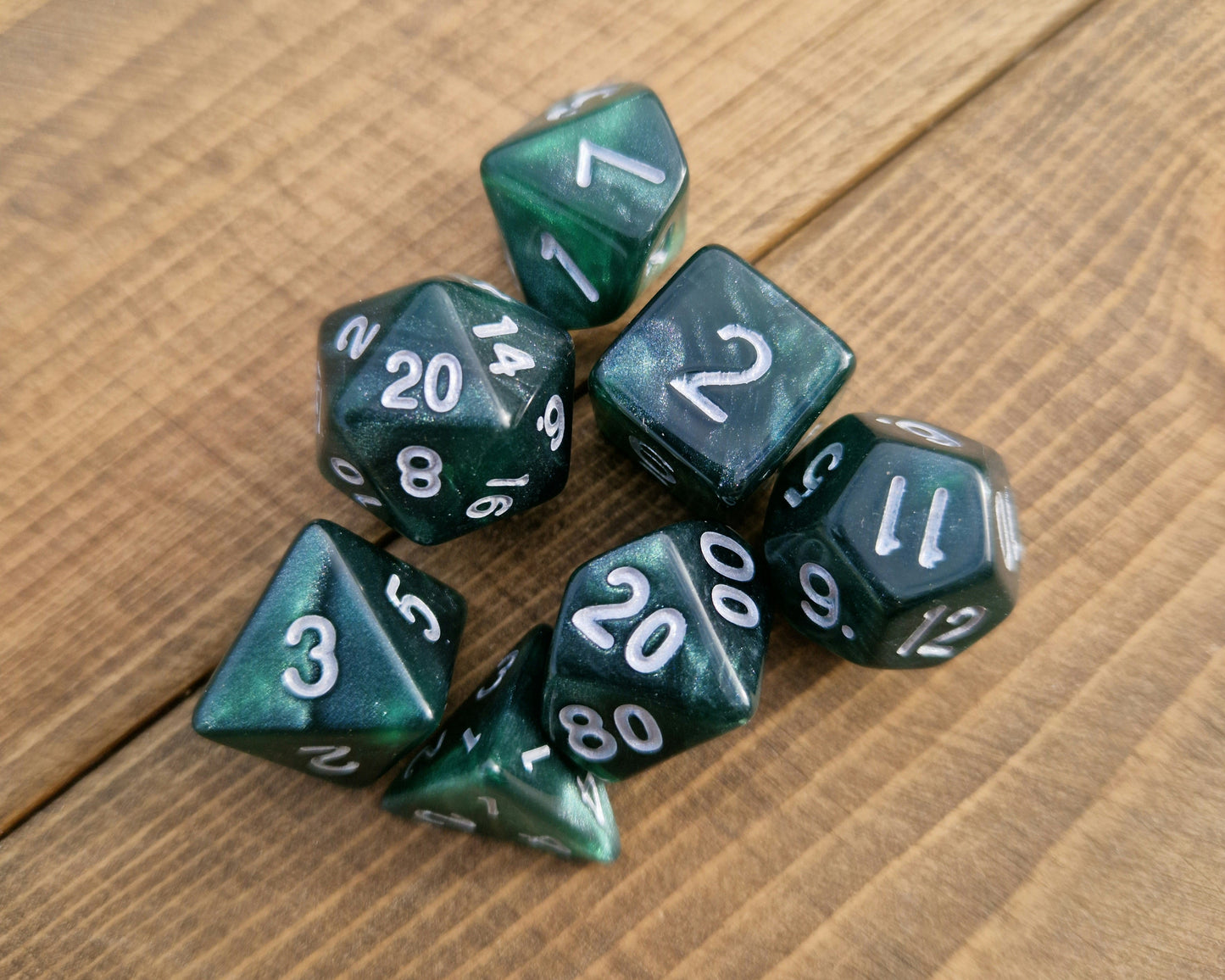 Polyhedral plastic dice set in shimmering dark green with white numbers