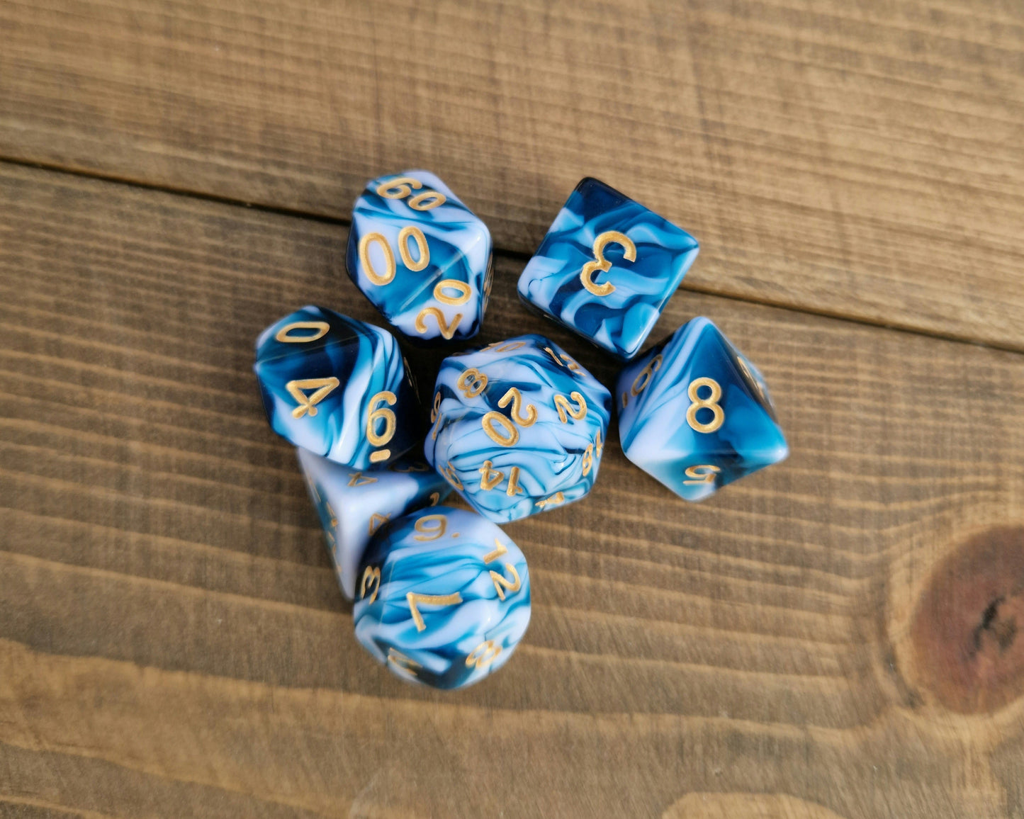 blue and white mabled polyhedral dice with gold numbers