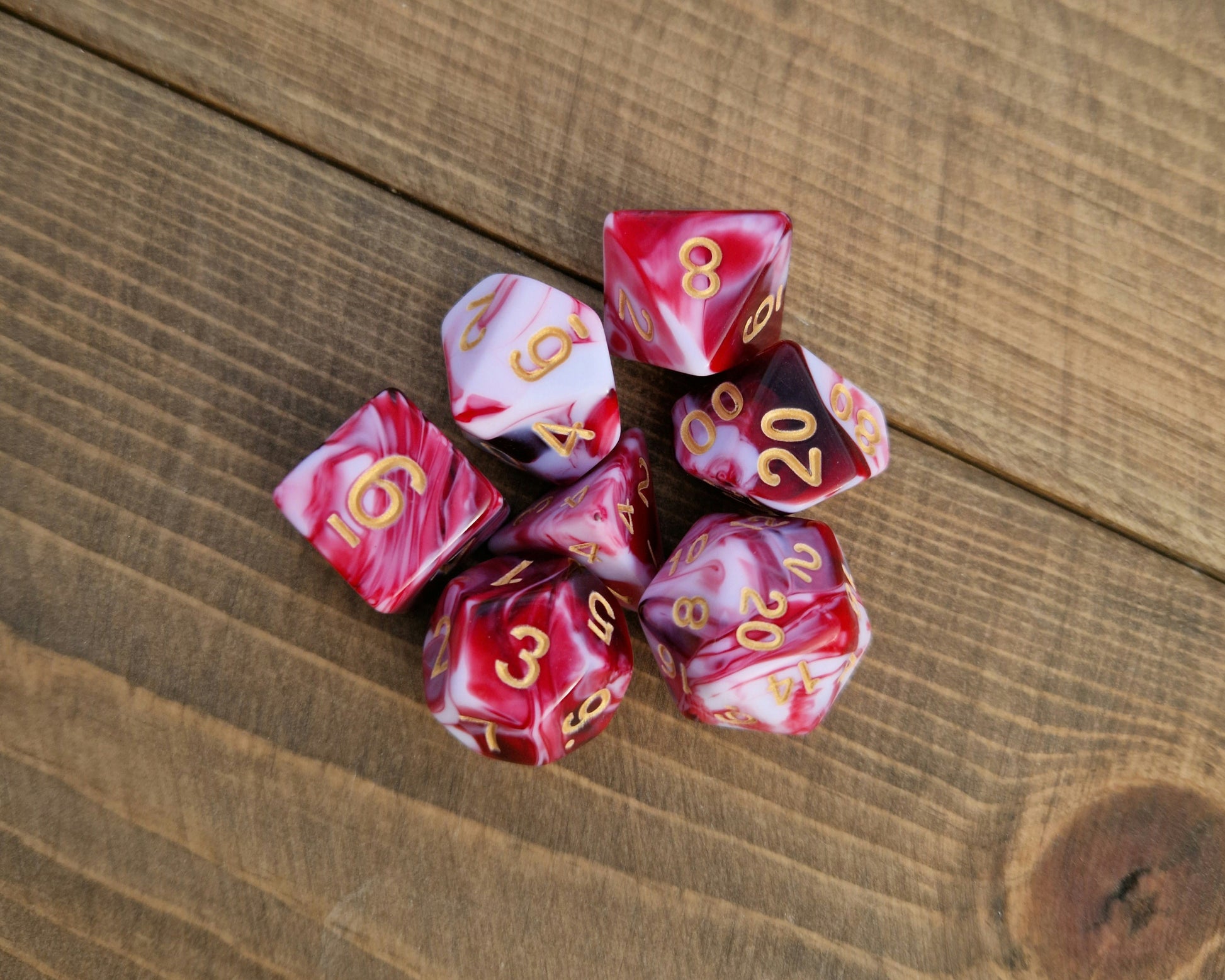 red and white marbled polyhedral dice set with gold numbers